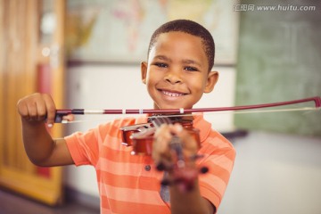 微笑的男生在课堂上拉小提琴