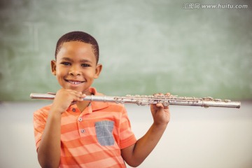 微笑的男学生在教室里吹长笛