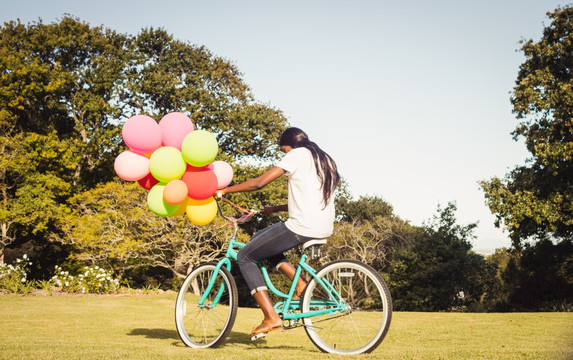 在骑自行车拿着气球泡的女人