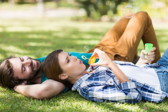 躺在公园草坪上吹泡泡的夫妇