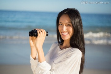 在海滩上使用望远镜的女人