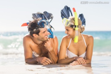 戴着潜水镜趴在海滩上的夫妇