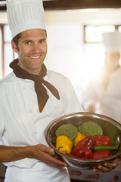 面带微笑的厨师展示一盆蔬菜食材