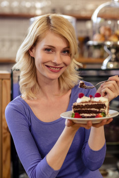 坐在咖啡馆里拿着蛋糕的女人