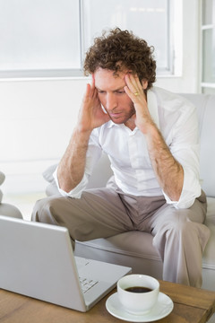 焦虑的男人坐在沙发上用电脑