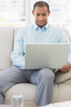 坐在沙发上使用笔记本电脑的男人