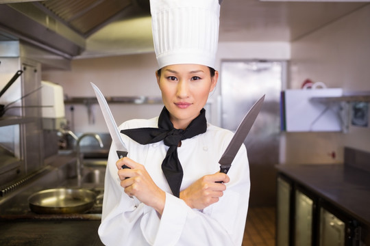一个自信的女厨师在厨房里拿着刀