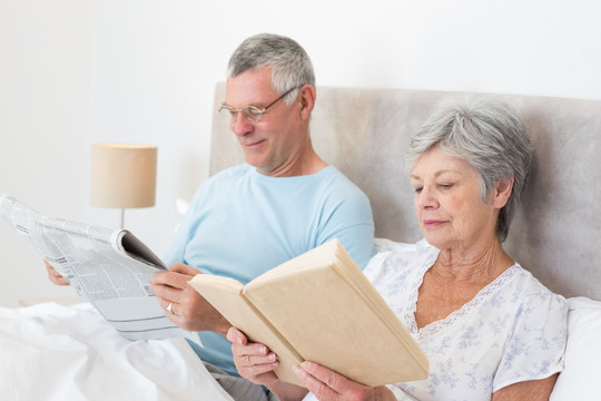 坐在床上阅读报纸看书的老夫妇
