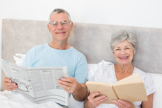 坐在床上阅读报纸看书的老夫妇