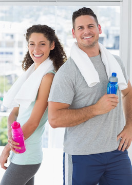 拿着水瓶在健身房里的一对夫妇