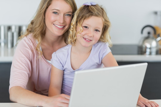 在教女儿使用笔记本电脑的母亲
