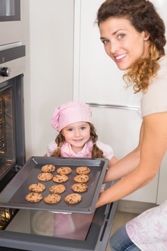 从烤箱里取出饼干的年轻母亲