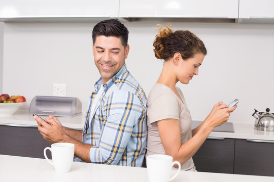在厨房里使用手机的年轻夫妇