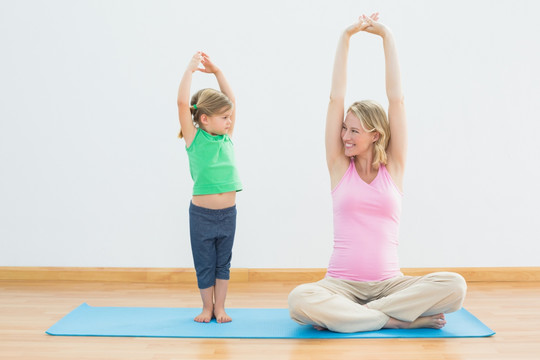 孕妇妈妈和女儿一起健身房做瑜伽