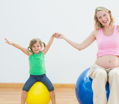 坐在健身球上的孕妇和小女孩