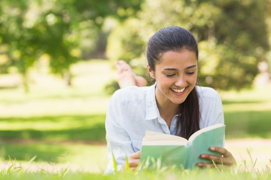 微笑的年轻女子在公园里看书