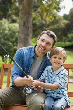 微笑的父亲和儿子在公园里钓鱼