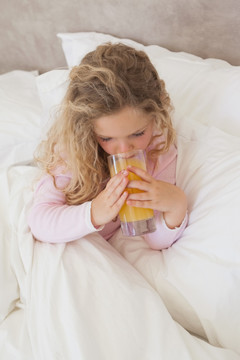 女孩在床上喝橙汁