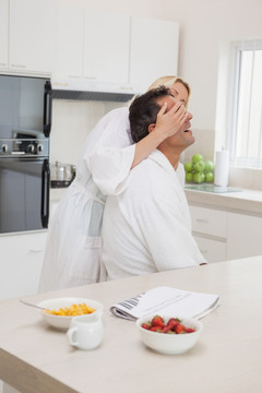在厨房里遮住丈夫眼睛的女人
