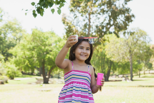 快乐的小女孩在公园吹肥皂泡
