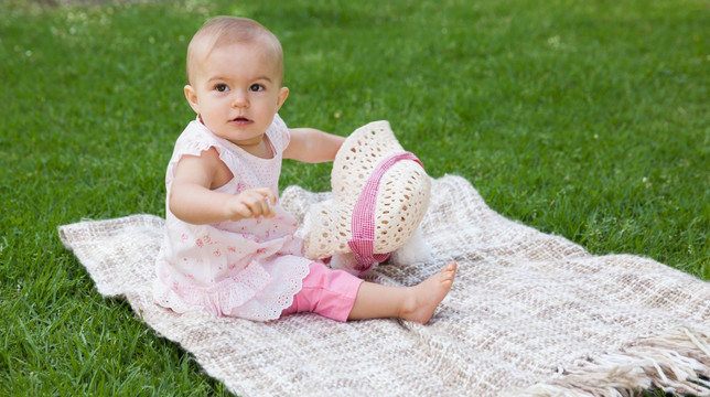 可爱的婴儿坐在公园的毯子上
