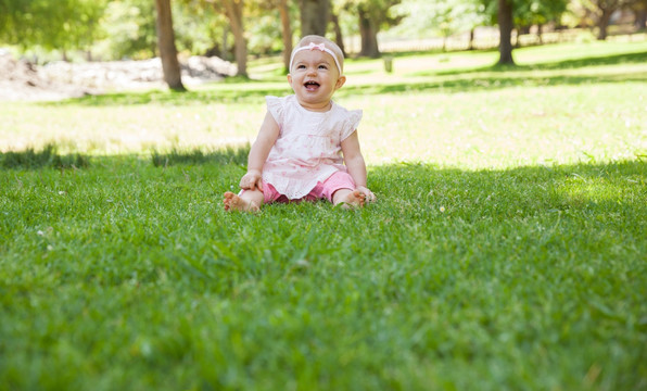 婴儿坐在公园的草地上