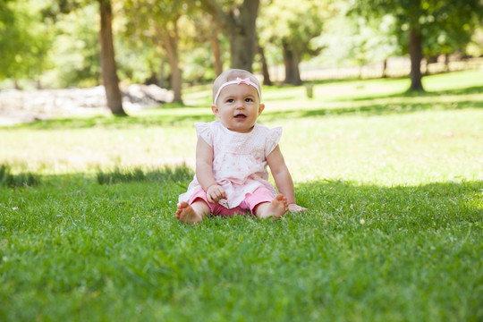 婴儿坐在公园的草地上