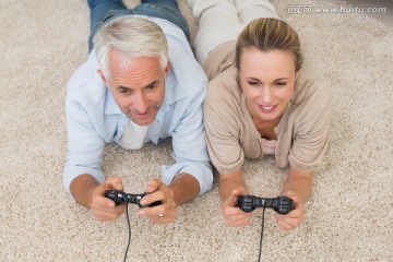 趴在毯子上玩电子游戏的夫妇