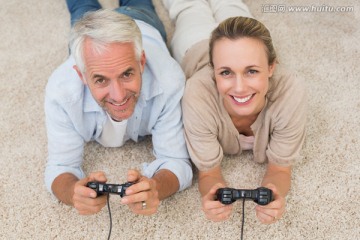 夫妇趴在地毯上玩电子游戏
