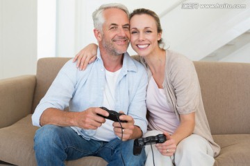 夫妇坐在客厅沙发上玩电子游戏