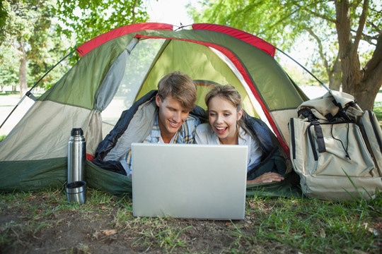 趴在帐篷里用笔记本电脑的夫妇