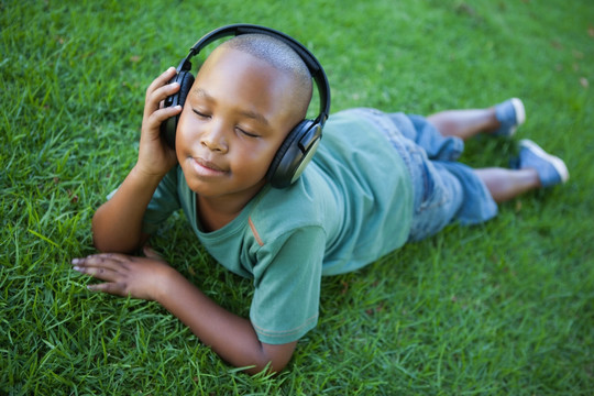 躺在草地上听歌的小男孩