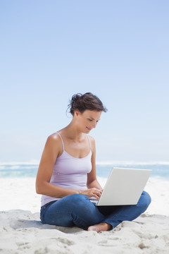 坐在海滩上用笔记本电脑的女人