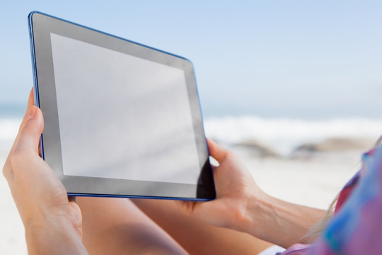 坐在沙滩椅上用平板电脑的女人