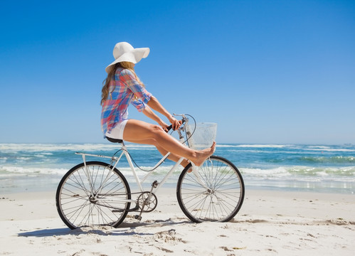 在海滩上骑着自行车的女人