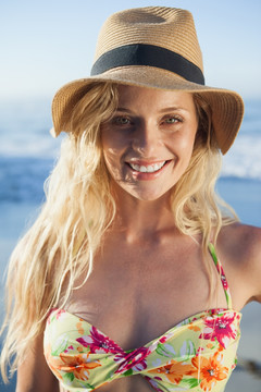 戴着太阳帽在海边的微笑女人