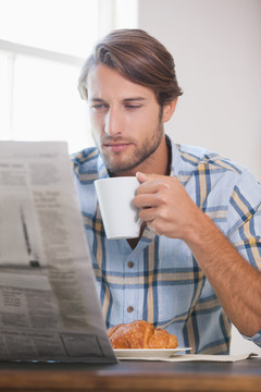 在家里喝咖啡和看报纸的男人