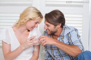 坐在地板上喝白葡萄酒的年轻夫妇