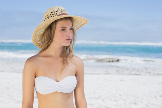 戴着帽子的女人站在沙滩上