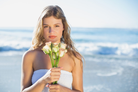 在海滩上手捧玫瑰的女人