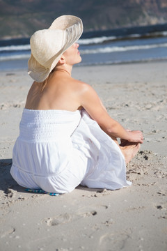 穿着白裙坐在沙滩上的女人