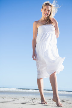穿着白裙站在沙滩上的女人