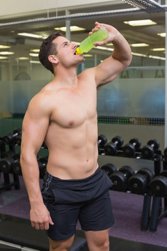 在健身房里喝水的肌肉男人