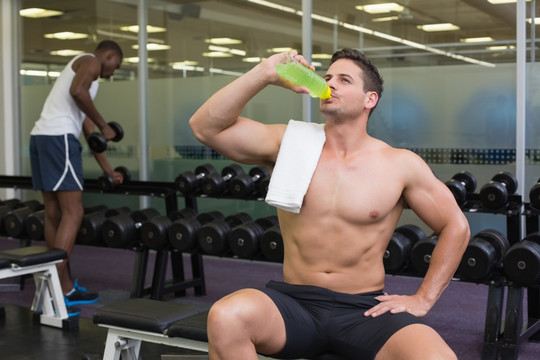 在健身房里喝水的男运动员