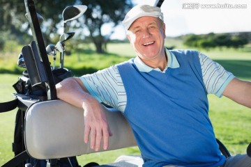 微笑的男人坐在高尔夫球车上