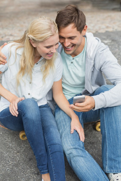 坐在滑板上看手机的夫妇