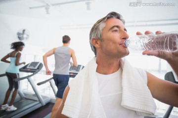 拿着瓶子喝水的健身男人