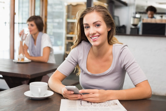 微笑的女人在咖啡馆里使用手机