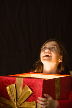 抬起头的小女孩拿着圣诞礼物