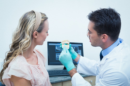 牙医拿着口腔模型为病人作解释